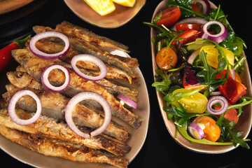 Fried herring fish with lemon, salad, and sauce.