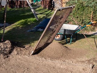 Erde wird im Garten gesiebt im Frühling