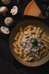 Fusilli pasta, with champignons in cream sauce, top view, with ingredients, on a wooden table, no people,