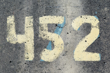 Four hundred and fifty two number painted with yellow paint on сoncrete wall. Hand drawing four,...