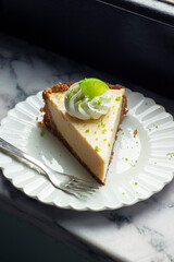 Slice of Key Lime Pie with Whipped Cream and Lime Zest on a Plate