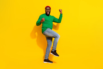 Fototapeta na wymiar Photo of glad successful man celebrate victory wear specs red beanie green shirt isolated yellow color background