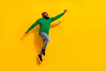 Fototapeta na wymiar Profile photo of energetic hero guy jump enjoy flight wear red beanie green shirt isolated yellow color background