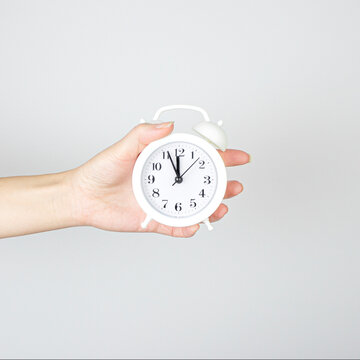 Hand Holds Little White Alarm Clock In Hand, Shows How Much Time Left.