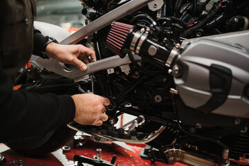 Fototapeta na wymiar Repairman repair motorcycle, maintenance in garage. Mechanic fixing bike in a modern shop