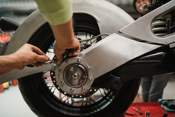 Repairman repair motorcycle, maintenance in garage. Mechanic fixing bike in a modern shop