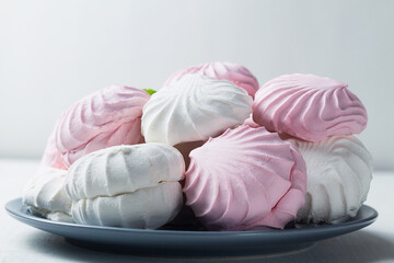 Pink and white Marshmallow dessert zephyr on the table. Meringue dessert with green mint in a grew plate on the white background. traditional Russian sweet dessert. copy space
