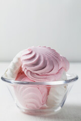 Airy Pink and white Marshmallow dessert zephyr on the table. Meringue dessert with green mint in a glass bowl on the white background. traditional Russian sweet dessert. copy space. vertical