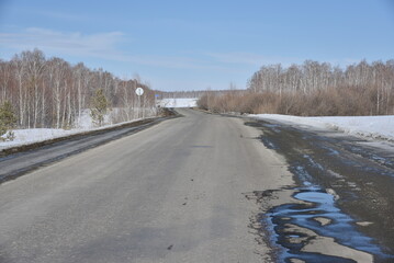 Highway in spring afternoon with puddles and snow