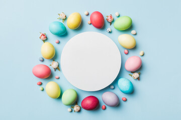 round frame multicolored Easter eggs with white blank paper on a brown background, close-up, space for text, blank for design, selective focus, tinted image