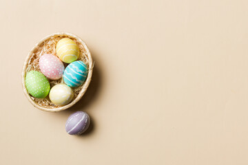 Multi colors Easter eggs in the woven basket on colored background . Pastel color Easter eggs. holiday concept with copy space