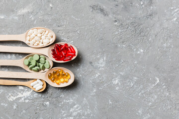 Top view Variety of vitamin and mineral pills in wooden spoon on Colored background. Top view of assorted pharmaceutical medicine pills. Dietary supplement healthcare product