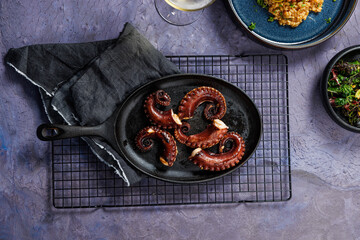 A portion of risotto with octopus tentacles. purple background. Top view