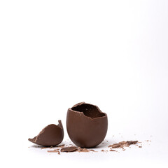 Cracked chocolate easter egg on light background, copy space. Broken milk chocolate egg with lid. Chocolate Easter concept.