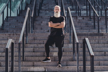 Full length photo of aged white hair strong man folded arms wear black t-shirt shorts sneakers outside in city