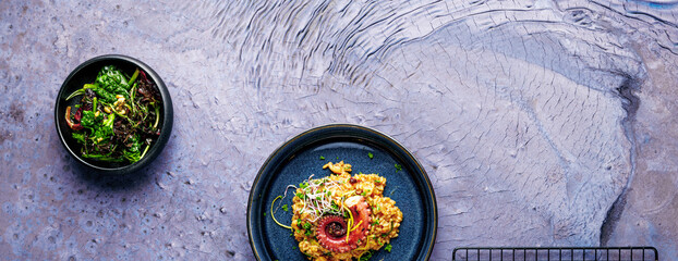 A portion of risotto with octopus tentacles. purple background. Top view