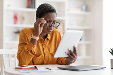 Black businesswoman using digital tablet, wearing eyeglasses, copy space