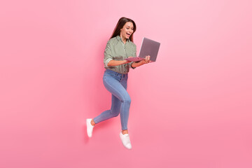 Photo of funny excited woman wear striped shirt typing modern device jumping high isolated pink color background