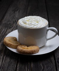 hot drink coffee or tea with whipped cream with heart shaped cookies on dark wooden background
