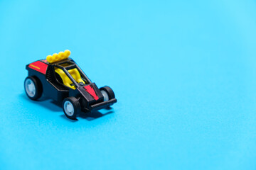 Fototapeta premium A black racing toy car on a blue background, a banner for a toy store with space for text