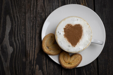 hot drink coffee or tea with whipped cream with heart shaped cookies and decor on dark wooden background with copy space flat lay