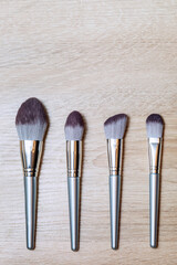 A set of makeup brushes of different shapes lies on the makeup artist's table parallel to each...