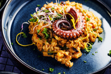 A portion of risotto with octopus tentacles. purple background. Top view © karepa
