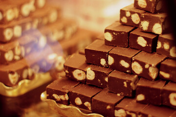 a showcase with sweets laid out in a stack. chocolate nougat with nuts