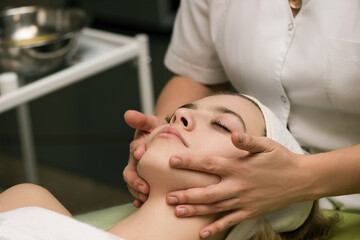 Face massage. Spa skin and body care. Close-up of young woman getting spa massage treatment at...