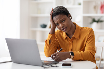 Bored black lady attending webinar, sitting in front of laptop