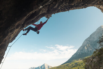 rock climber climbs a difficult route on a rock in the form of an arch