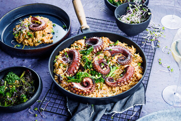 A portion of risotto with octopus tentacles. purple background. Top view