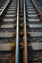 Naklejka premium The railroad tracks passed through the yellow grooved bearings buried under small shards of rock.