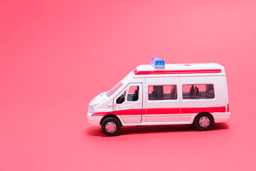 A white toy ambulance with red lines on a red background. Special transport, toy store.