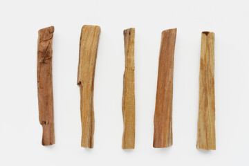 A top view image of several sticks of holy wood incense on a white background. 