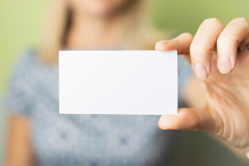 the girl's hand holds empty business card. background blurred
