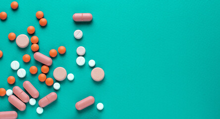 A lot of tablets on a turquoise background . probiotic capsule and antibiotic tablet