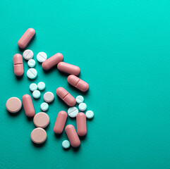 A lot of tablets on a turquoise background . probiotic capsule and antibiotic tablet