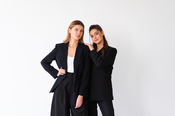 Concept of partnership in business. Two Young businesswoman dressed black formal suit standing studio isolated white background.