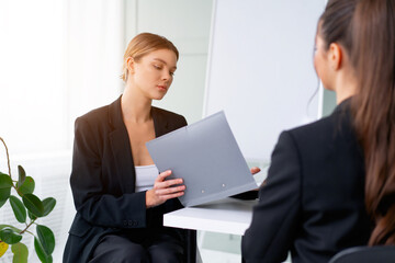 Job interview. Business, career and placement concept. Young blonde woman holding resume, while sitting in front of candidate during corporate meeting or job interview
