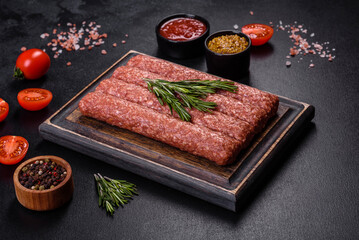 Fresh raw mince for grilled kebab with spices and herbs on a dark concrete background