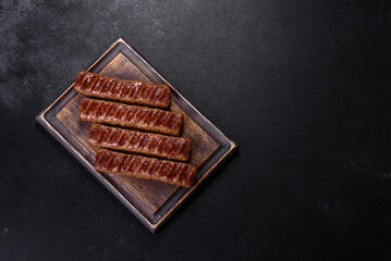 Grilled kebab with spices and herbs on a dark concrete background