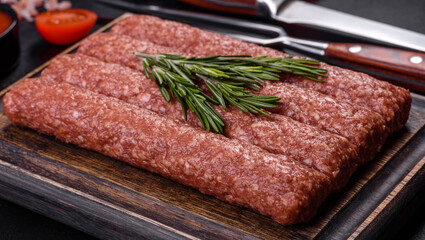 Fresh raw mince for grilled kebab with spices and herbs on a dark concrete background