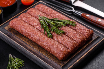 Fresh raw mince for grilled kebab with spices and herbs on a dark concrete background
