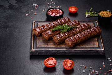 Grilled kebab with spices and herbs on a dark concrete background