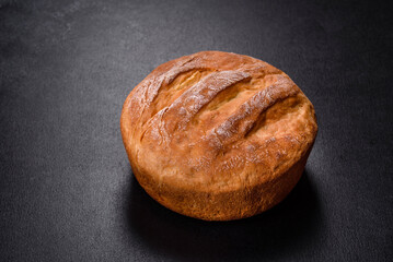 Tasty fresh baked in oven white bread on a dark concrete background