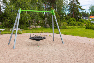 Beautiful view of children's swing on an empty playground on summer day. Sweden.