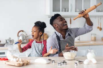 Funny african american family singing while baking at home