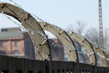 Betonowe ogrodzenie z drutu kolczastego w około obozu imigrantów. - obrazy, fototapety, plakaty