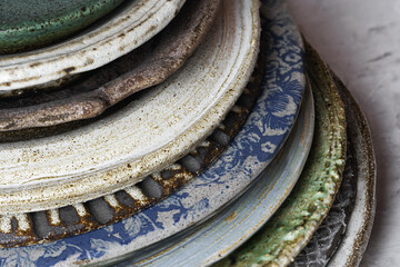Handmade ceramic plates of various textures and sizes are stacked. Close-up, selective focus. Handmade pottery..